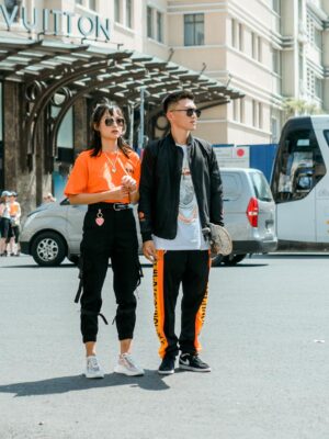 Fashionable couple posing in front of Louis Vuitton store with urban backdrop.