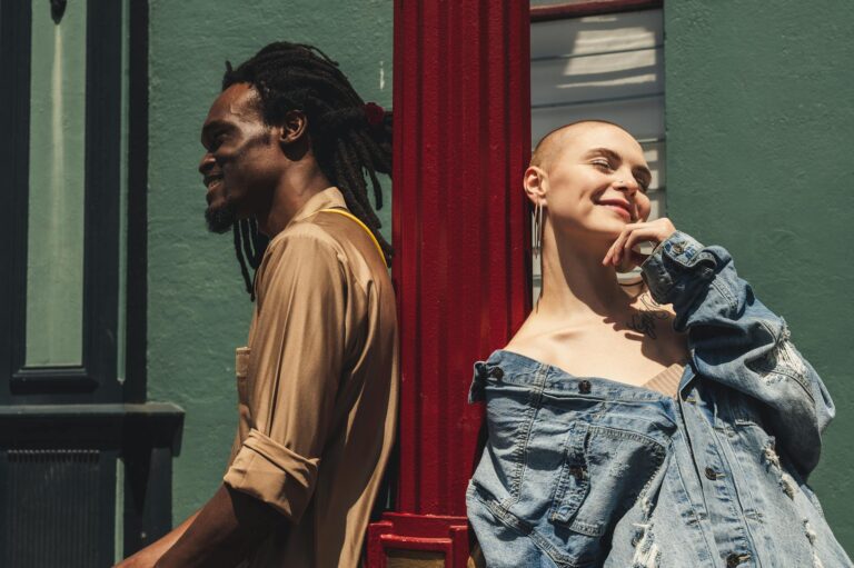 Trendy urban fashion shoot featuring diverse models leaning against a vibrant city backdrop.