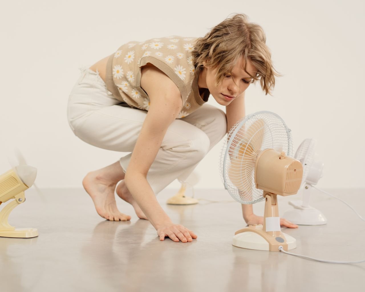 The Art of Drawing Readers In: Your attractive post title goes here Young woman observing several table fans in minimalist indoor studio setting.