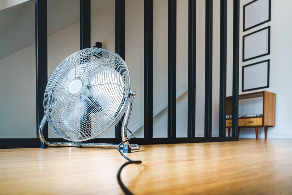 ventilateur électrique Un ventilateur électrique au design épuré, posé sur un sol en bois dans un intérieur moderne